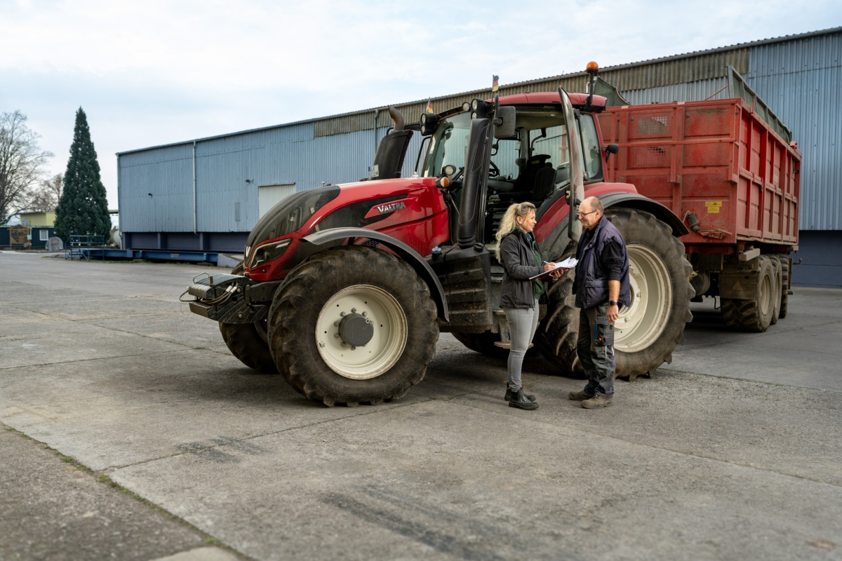 Katrin Beberhold auf ihrem Hof vor dem Traktor im Gespräch mit einer männlichen Person
