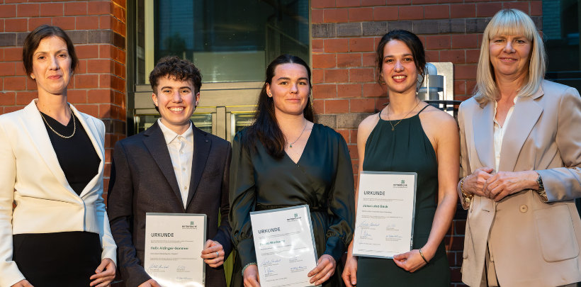 Fünf Personen (v.l.n.r.: Stefanie Sabet, Helix Aldinger-Sommer, Jana Beck, Paula Markwitz, Nikola Steinbock) stehen nebeneinander vor einem Backsteingebäude, drei halten Urkunden, alle tragen formelle Kleidung.